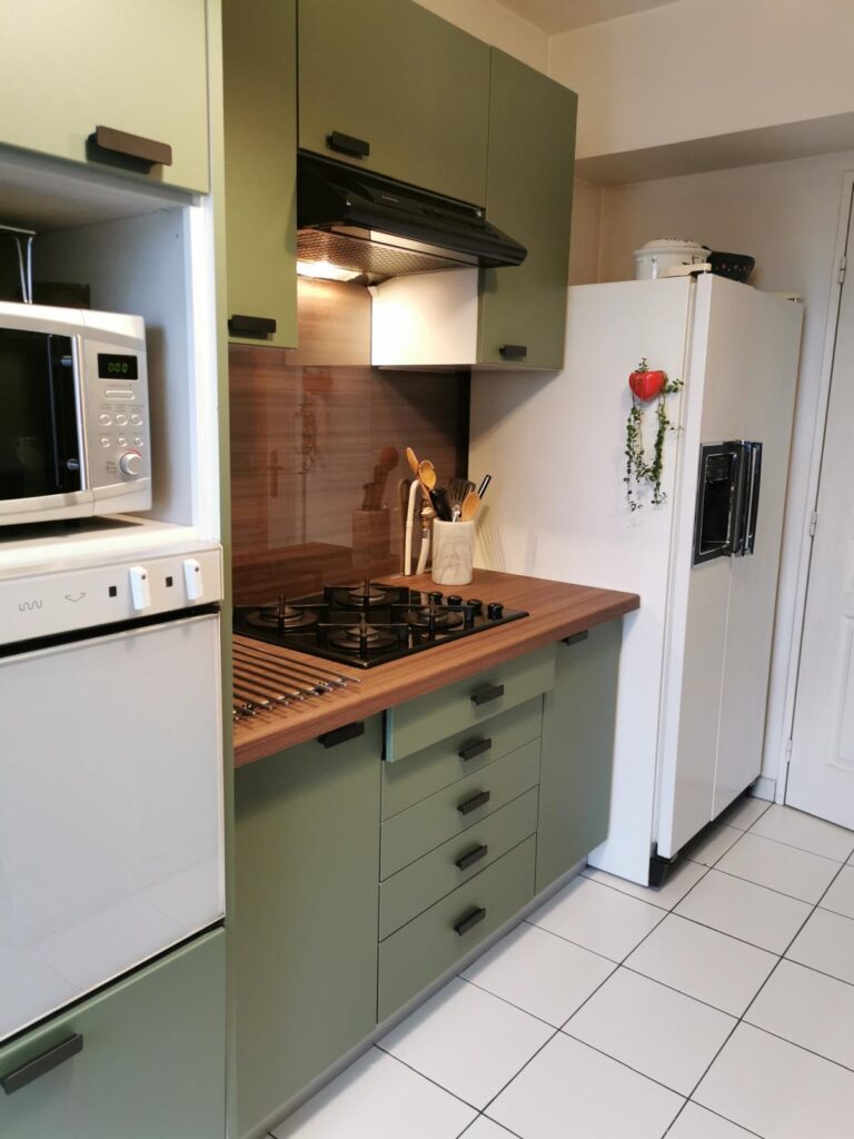 Cuisine verte avec plan de travail bois et électroménager blanc dans une ambiance moderne