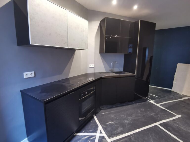 Cuisine moderne avec façades noires brillantes et placards hauts blancs mats en rénovation
